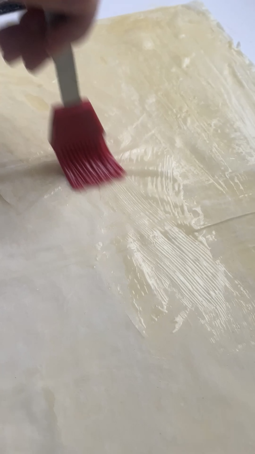 Buttering the phyllo with a pastry brush.