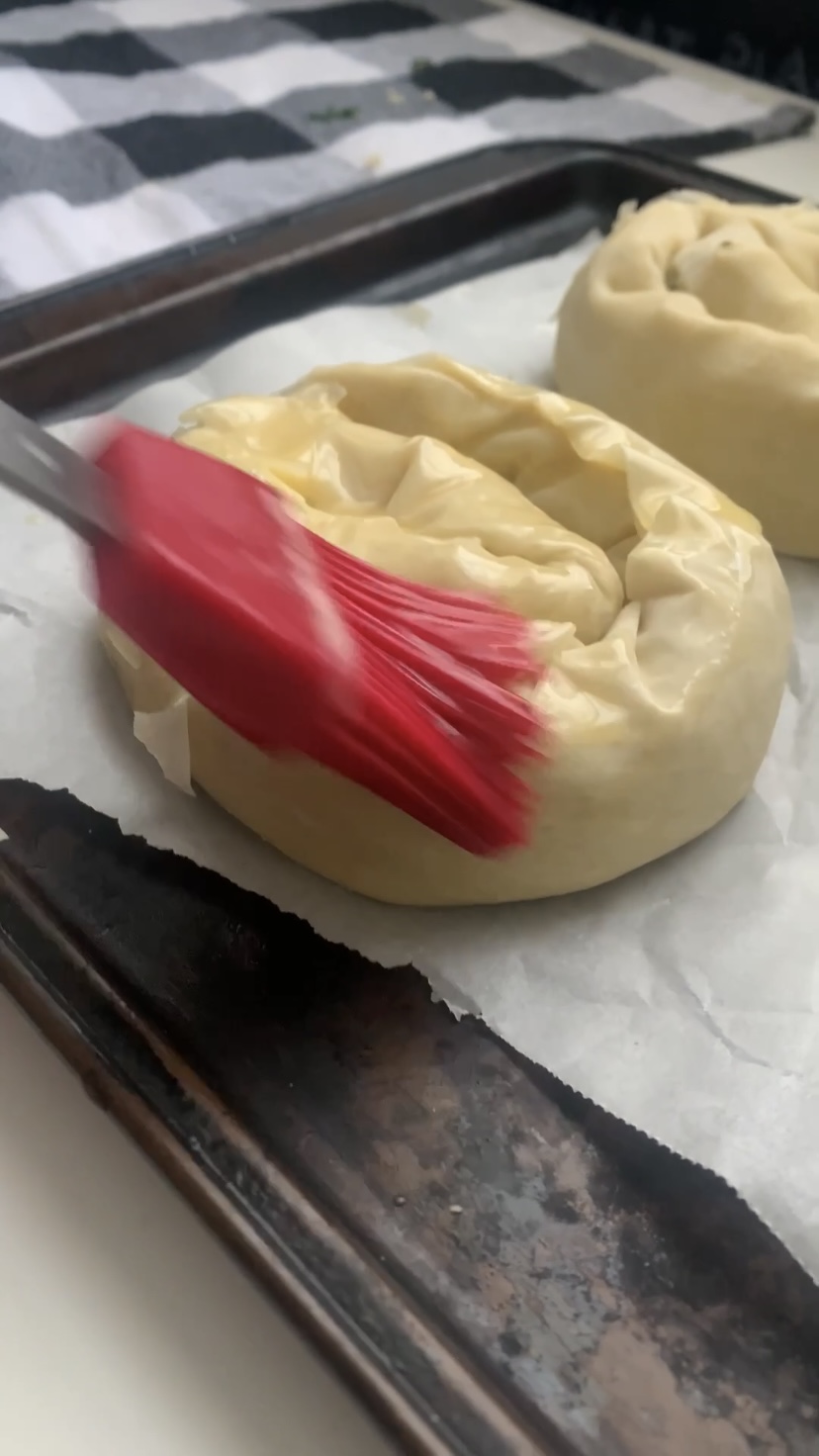 Brushing the spanakopita swirls with butter.
