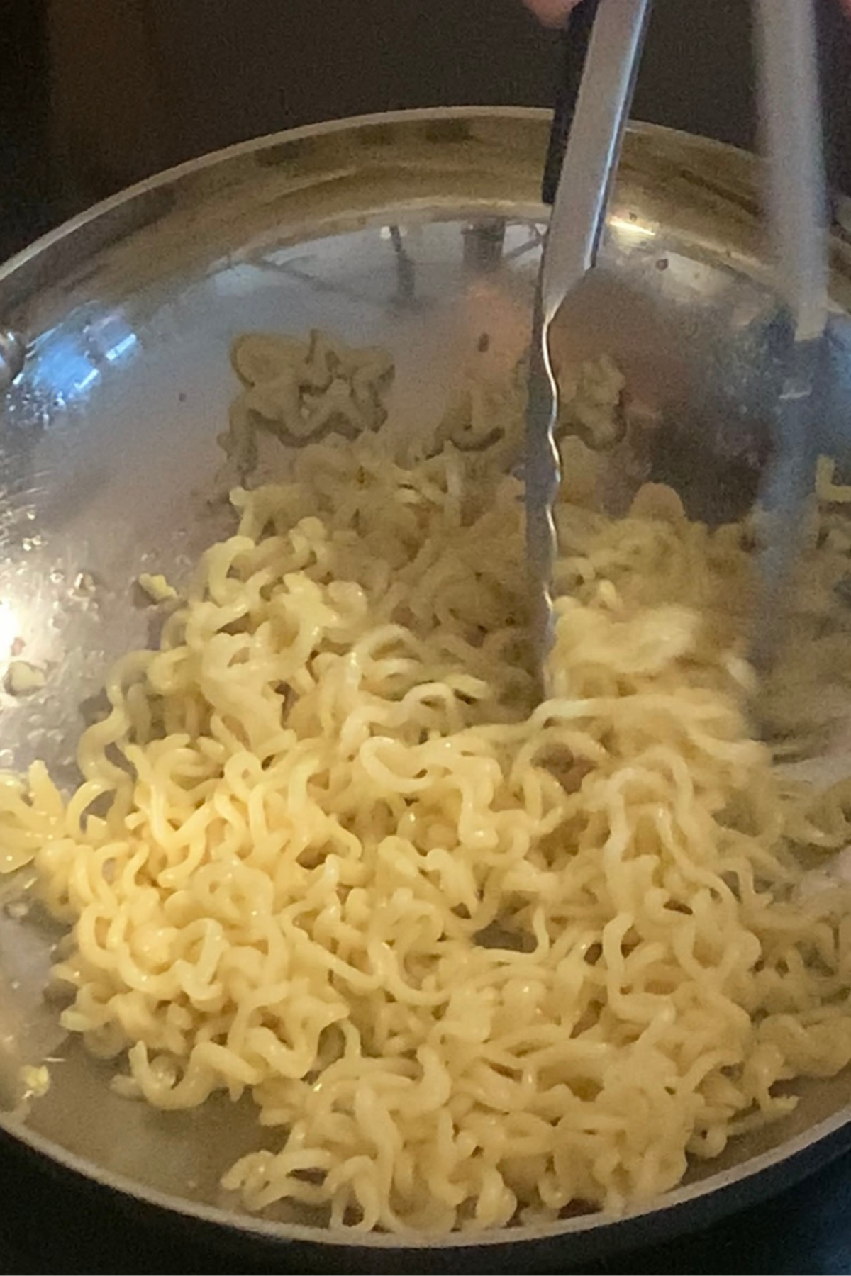 Mixing noodles with vegan garlic butter.
