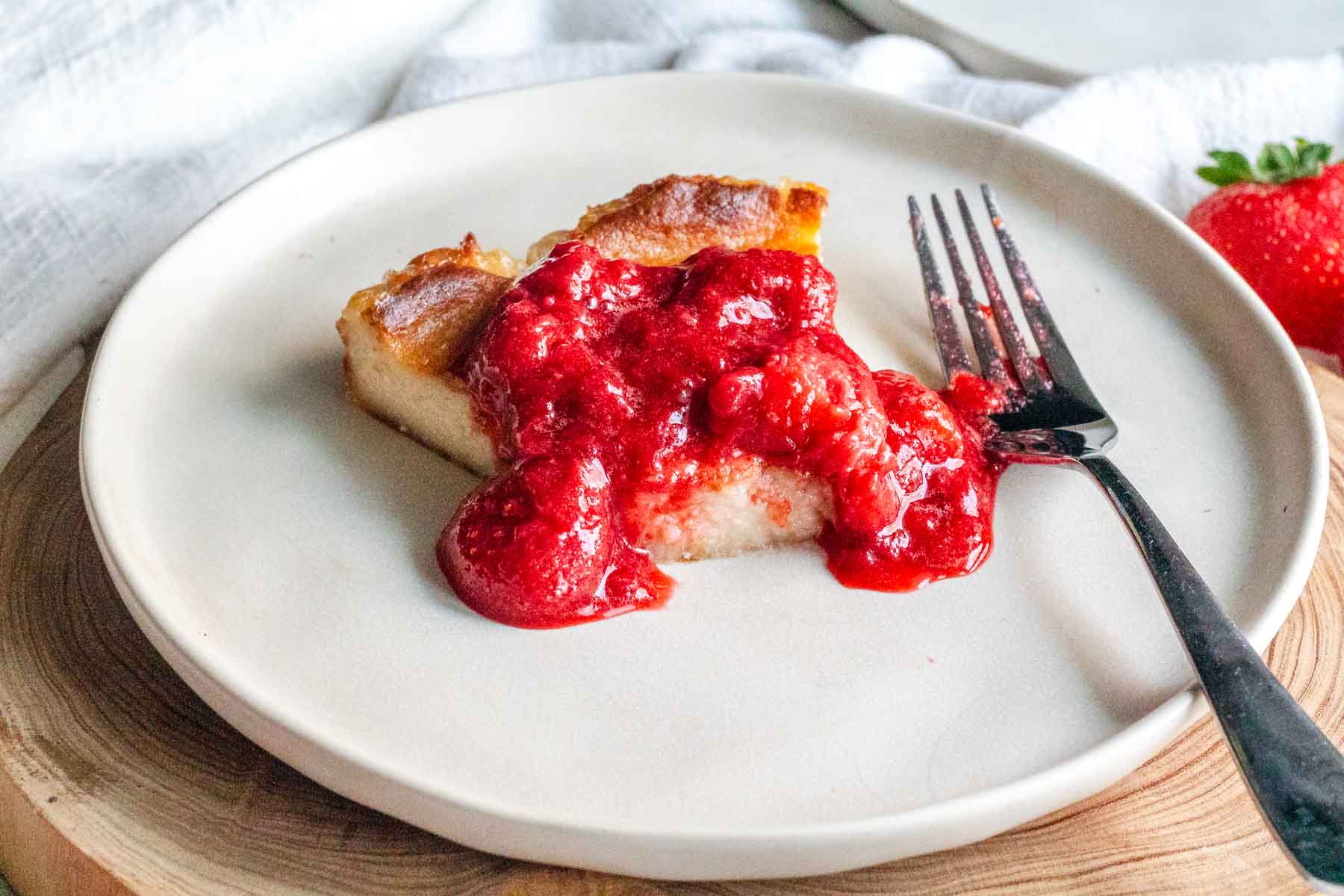 Vegan cheesecake with strawberry sauce with a fork.