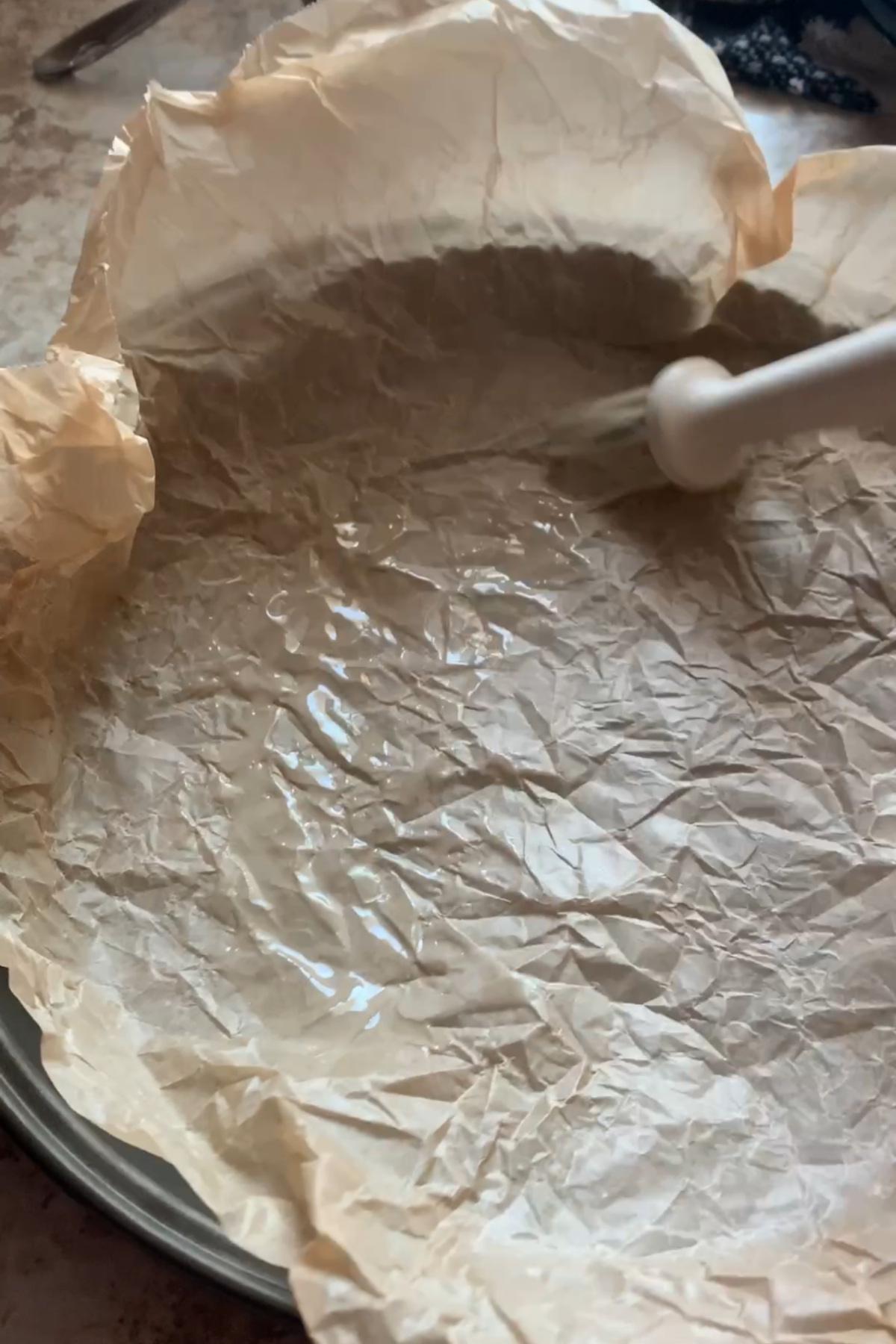 Brushing the parchment paper with butter.