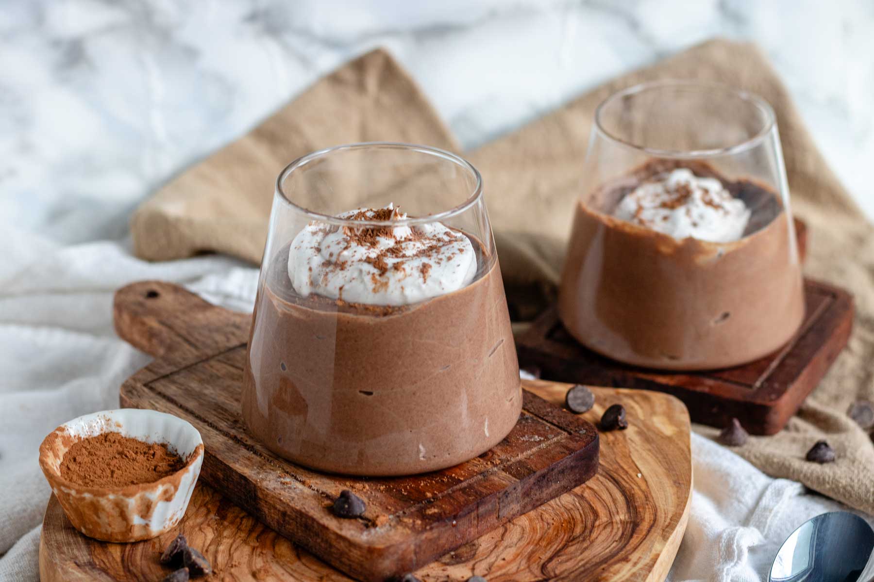 Chocolate tofu pudding with coconut whip in a glass on a wooden board.