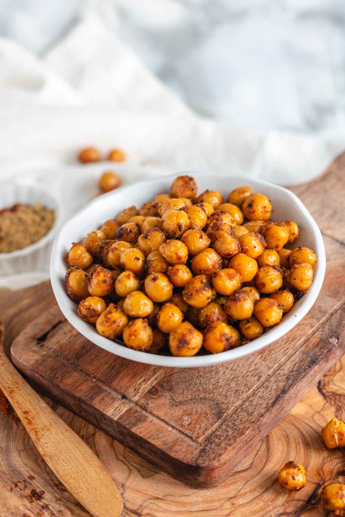 Pan fried chickpeas in a bowl on a wooden board.
