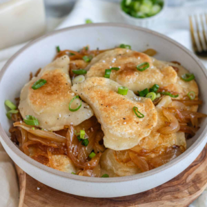 Fried pierogis in a bowl with onions.