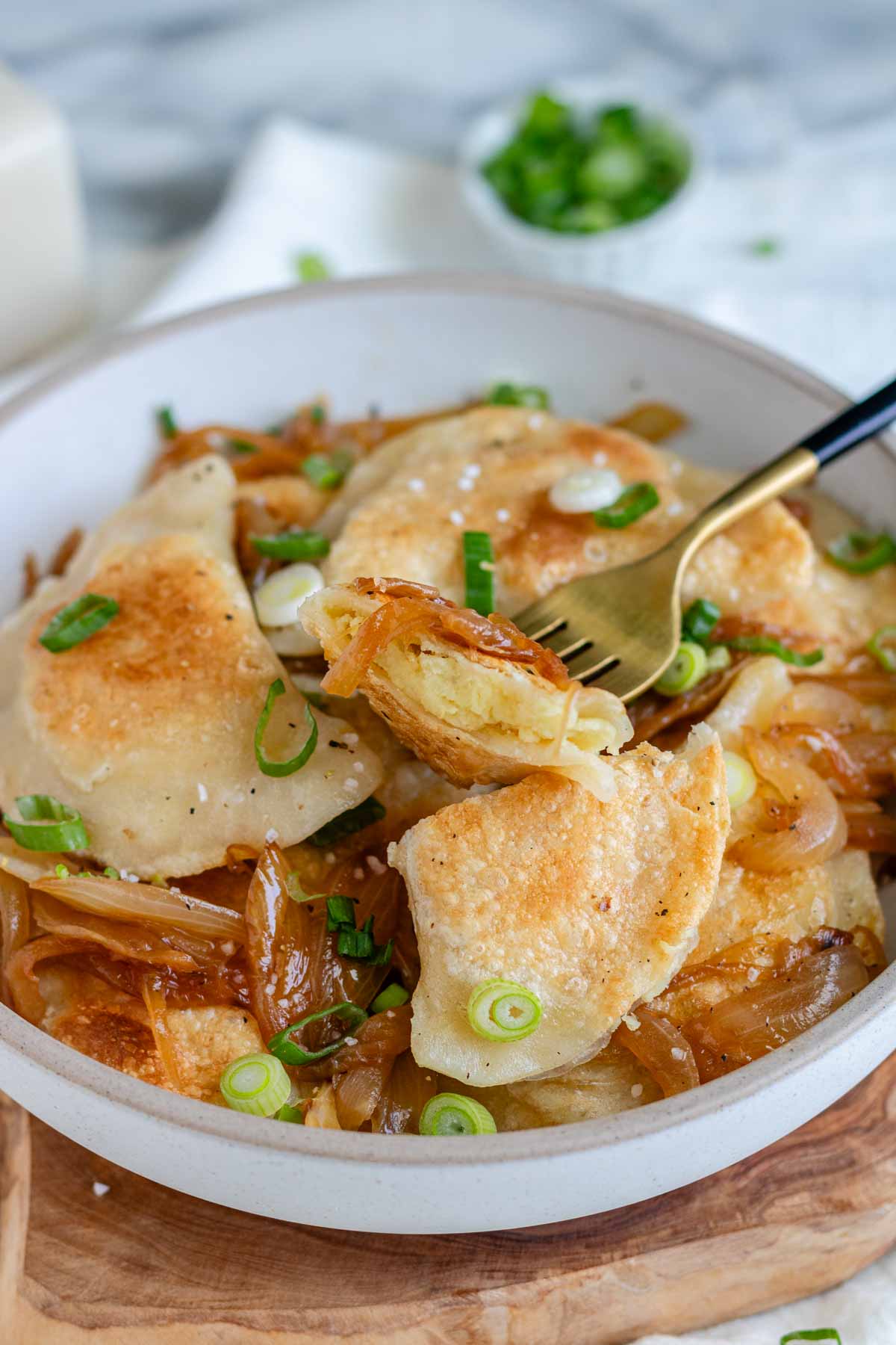 Vegan pierogis in a bowl with onion and a fork.