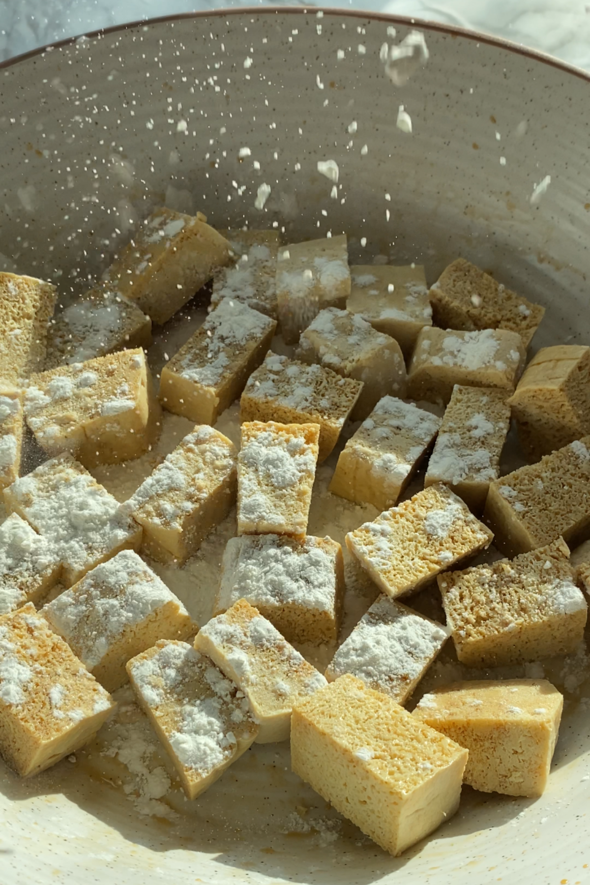 Corn starch sprinkled on tofu cubes.