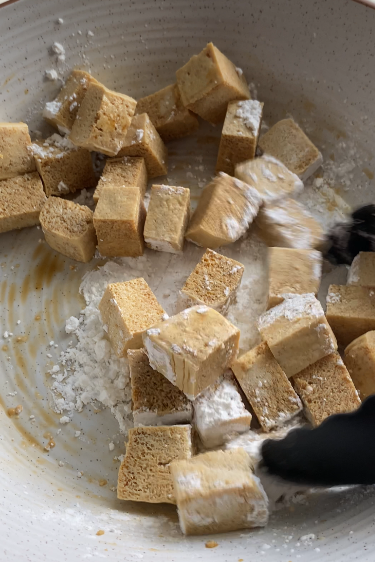 Mixing tofu with soya sauce and corn starch.
