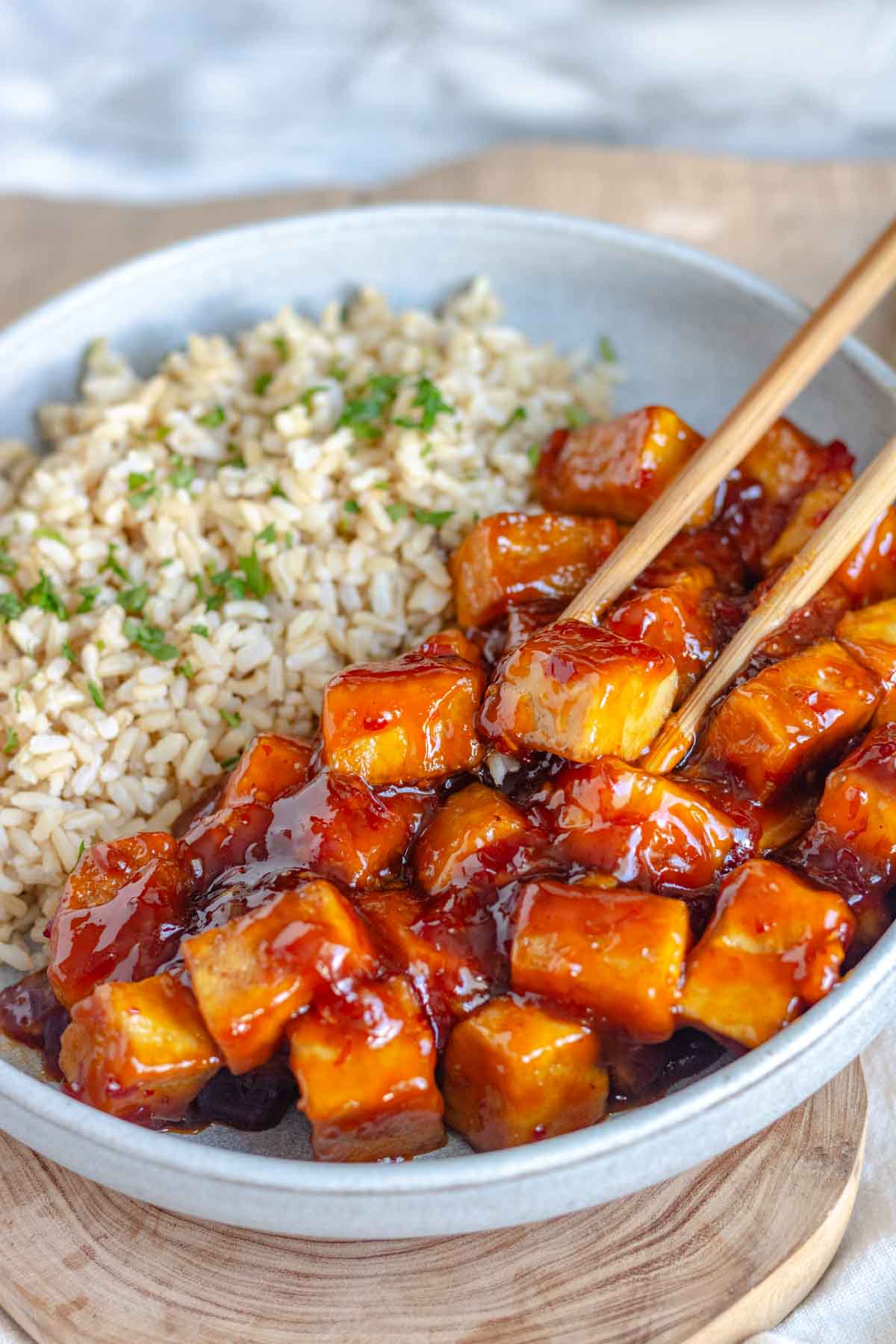 Sweet chili tofu and rice in a bowl with chopsticks.