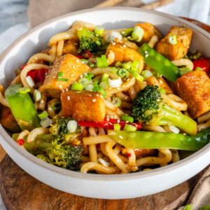 Tofu udon stir fry in a bowl topped with green onions.