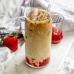 An iced latte swirled with bright strawberry sauce.