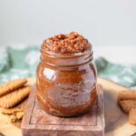 Biscoff spread in a glass jar on a wooden board.