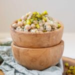 Dill pickle chickpea salad in a wooden bowl topped with chopped pickles.