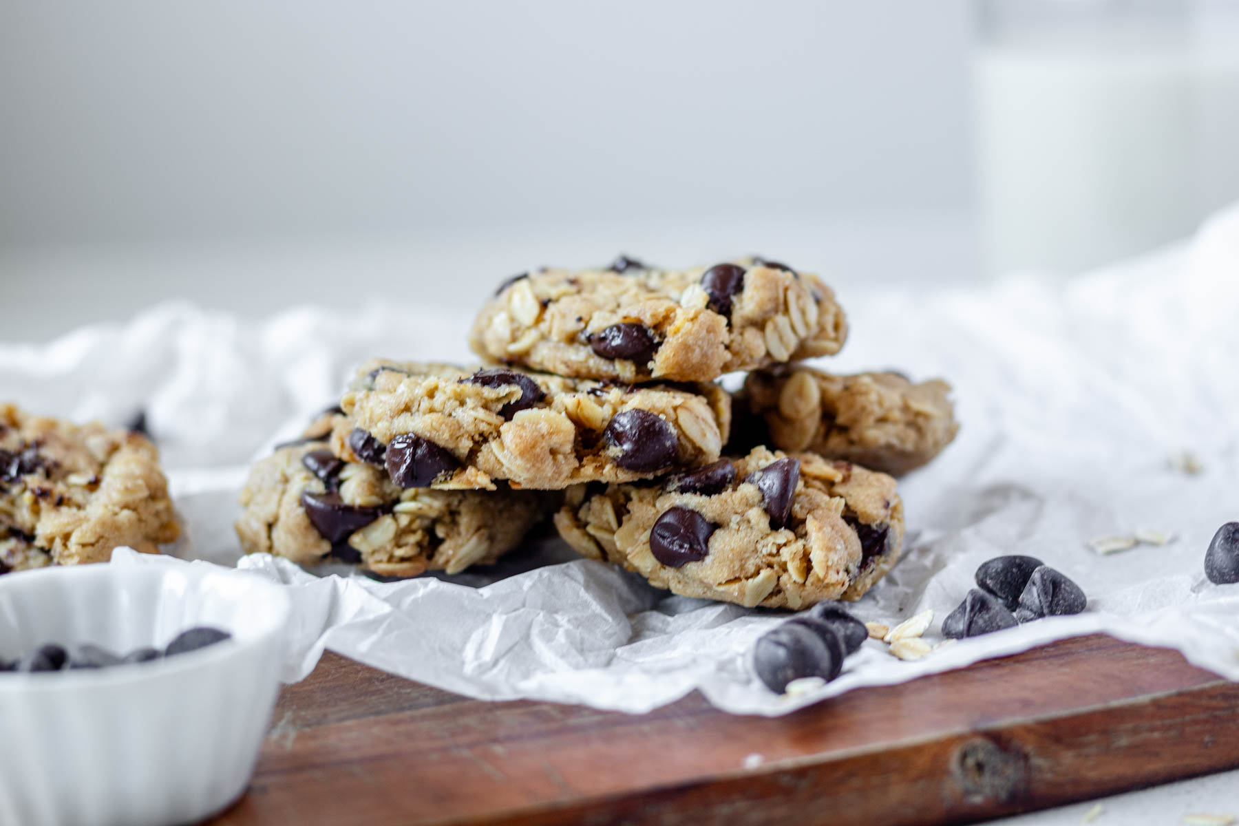Vegan oatmeal chocolate chip cookies piled on a piece of parchment paper.