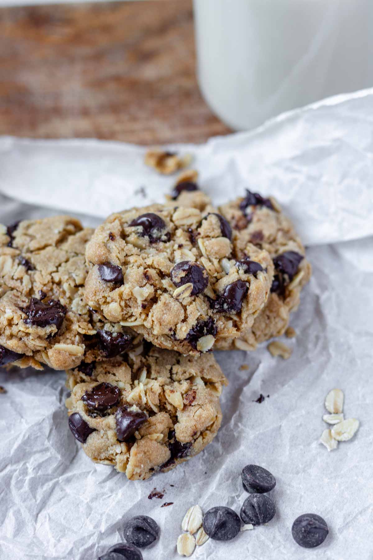 Vegan oatmeal chocolate chip cookies piled on a piece of parchment paper.