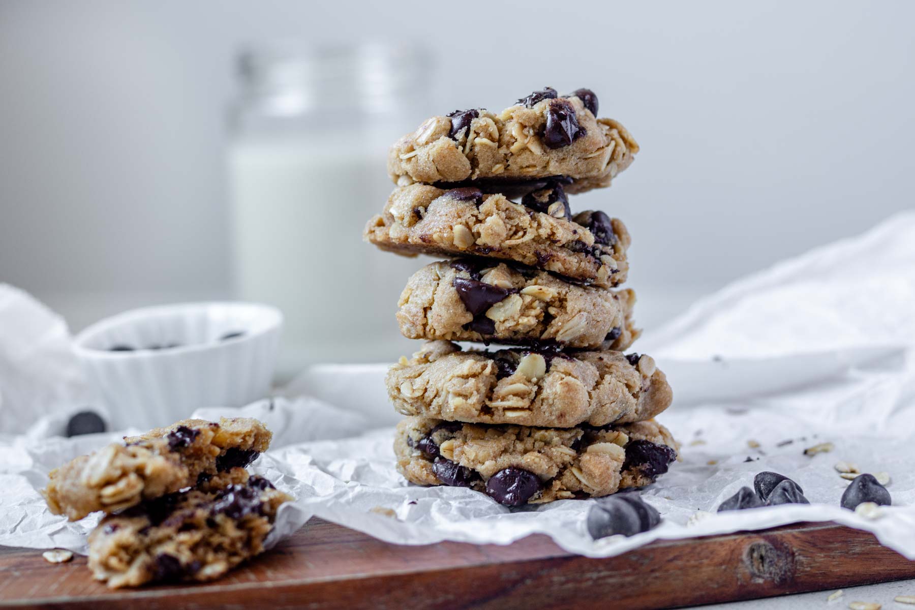 Vegan oatmeal chocolate chip cookies piled on a piece of parchment paper,