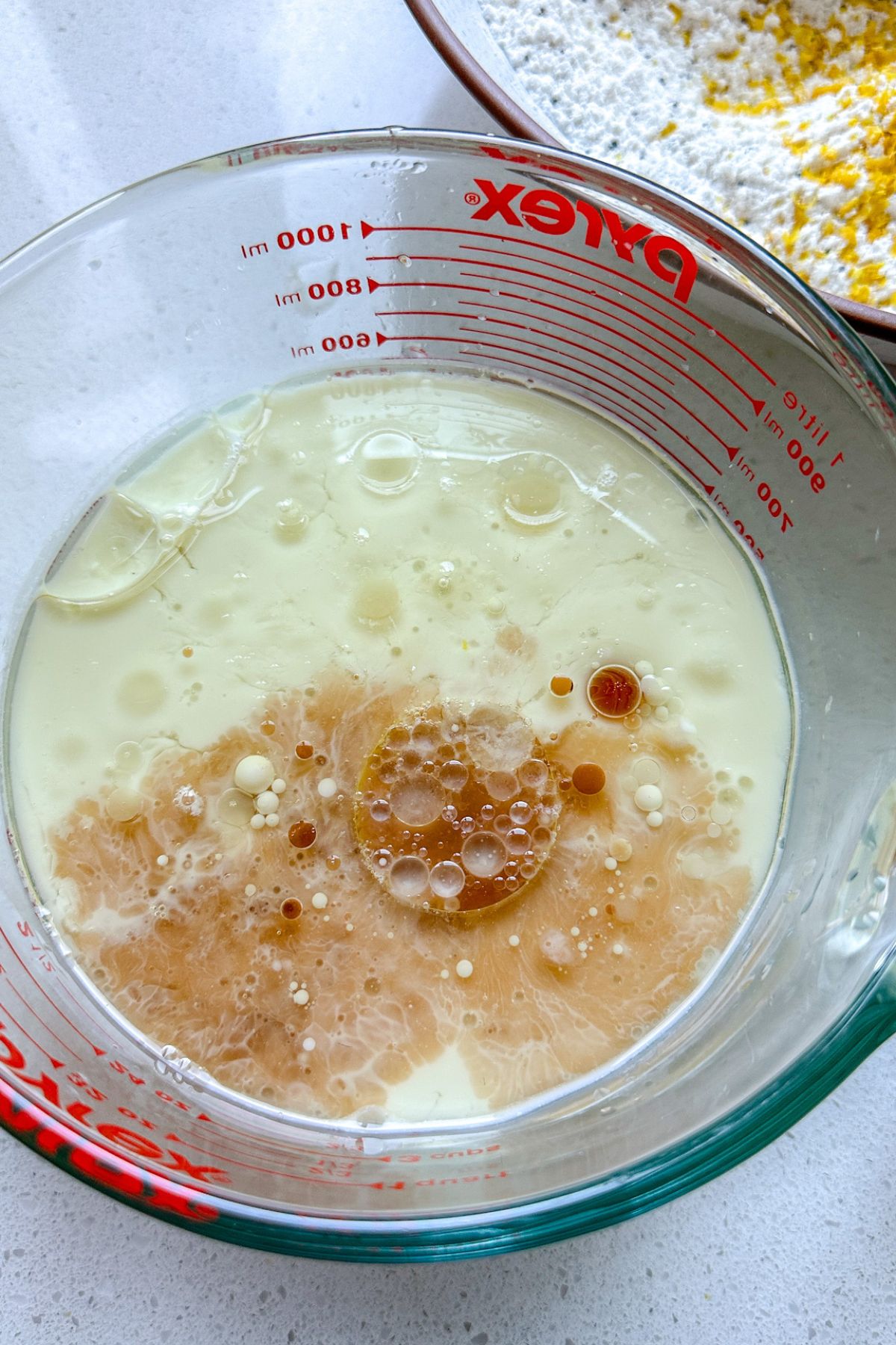 Lemon poppy seed cake wet ingredients in a glass measuring cup.