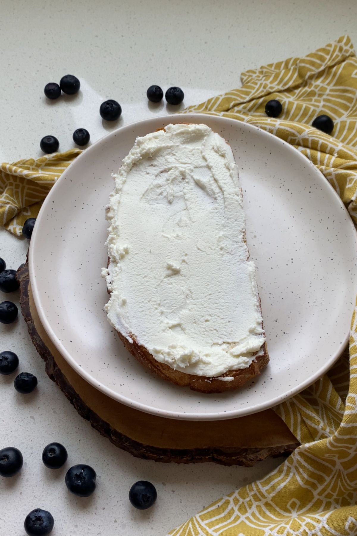 A piece of toast spread with goat cheese on a white plate.