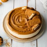 A whole cheesecake topped with a biscoff spread topping with whole and crushed cookies.