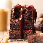 Three squares of brownie stacked with melted chocolate running down.