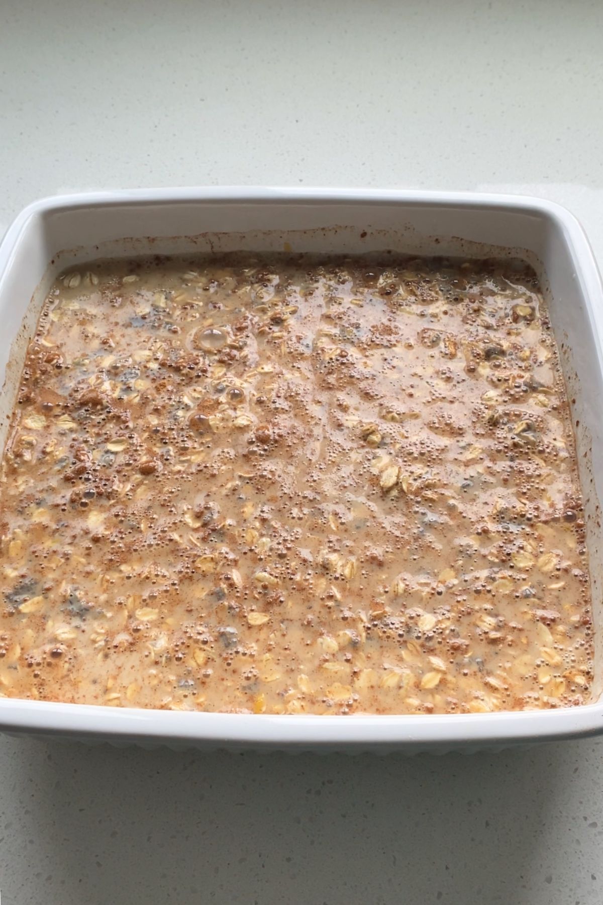 Unbaked oatmeal mixture in a white baking dish.