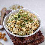Creamy chickpea salad in a white bowl topped with fresh dill.