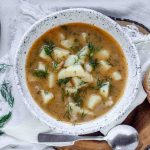 A bowl of potato dill soup topped with fresh dill.