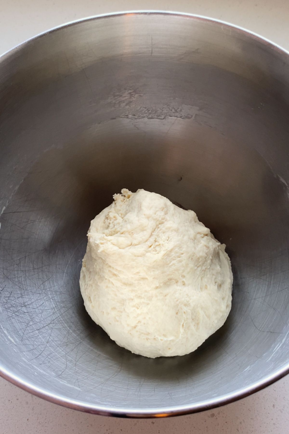 Dough in a stainless steel bowl.