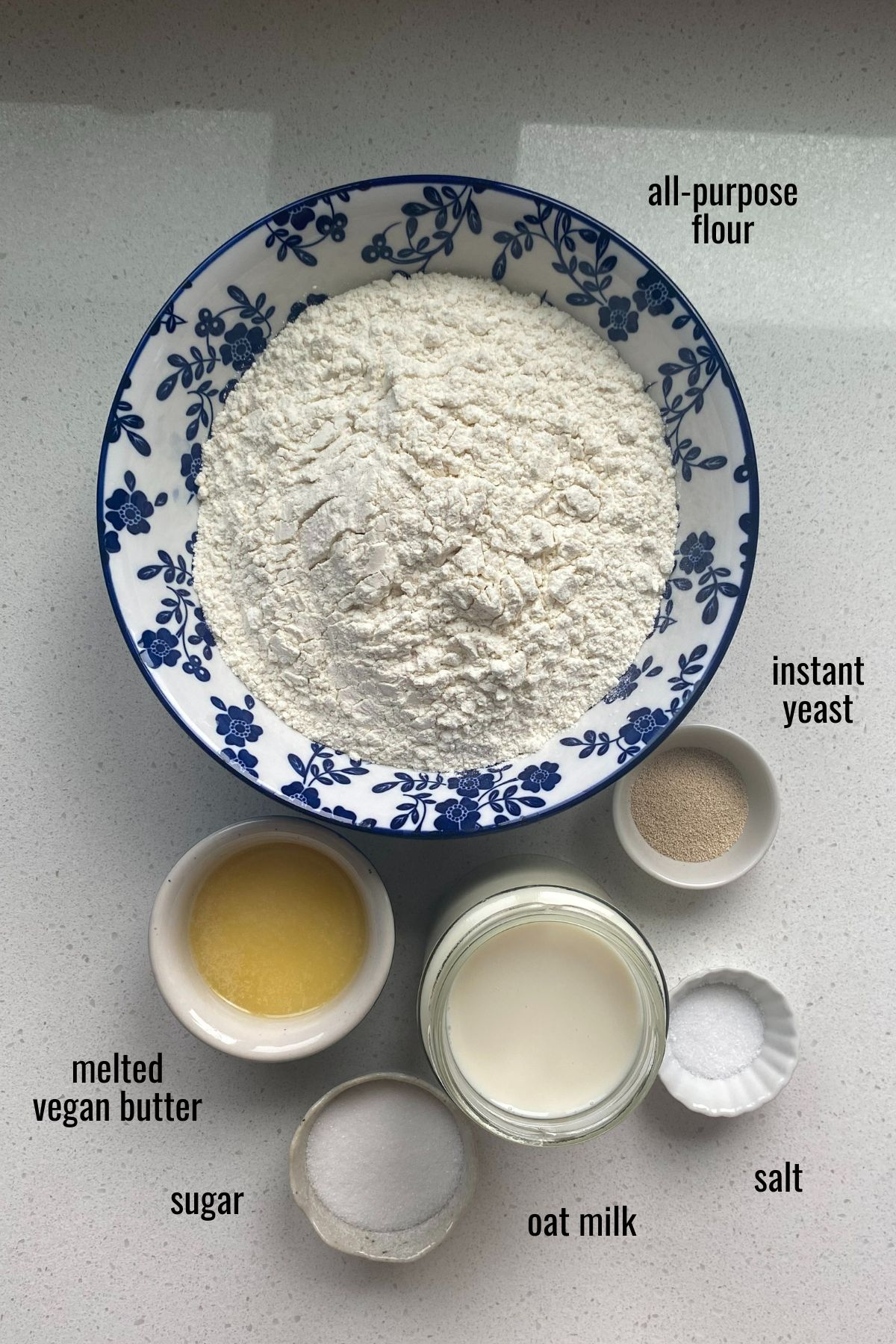 Ingredients for vegan hot dog buns in dishes on a white counter top.
