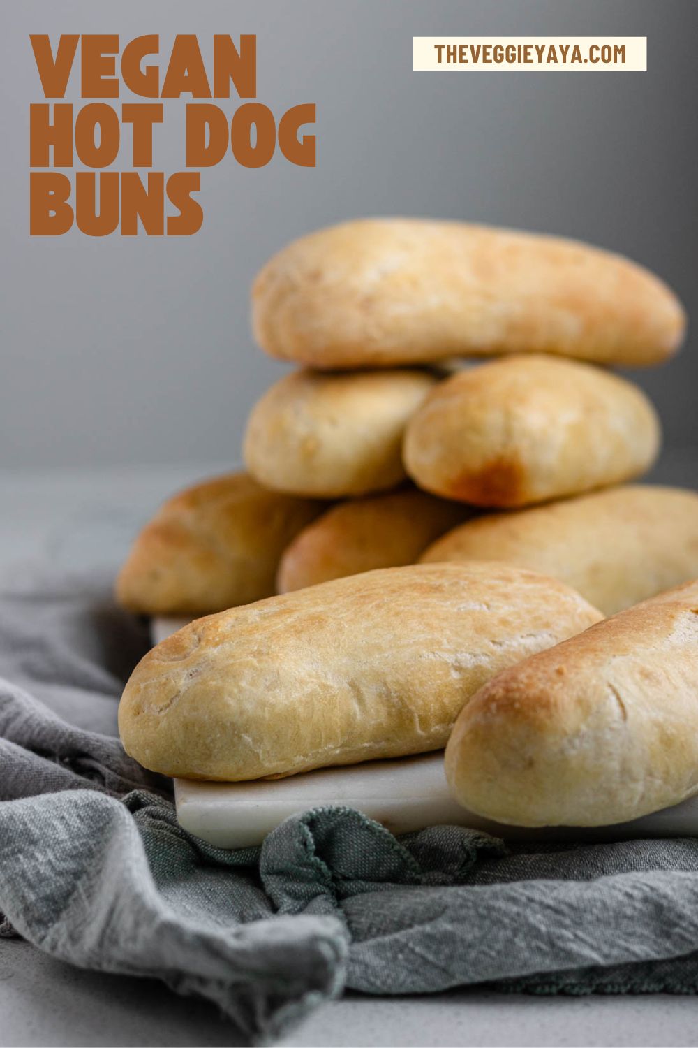Hot dog buns stacked on a white marble slab with brown text above.