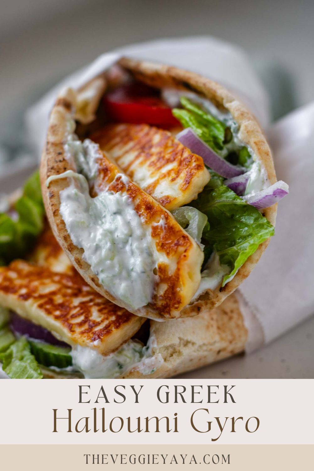 A halloumi gyro wrapped in parchment paper with text below.
