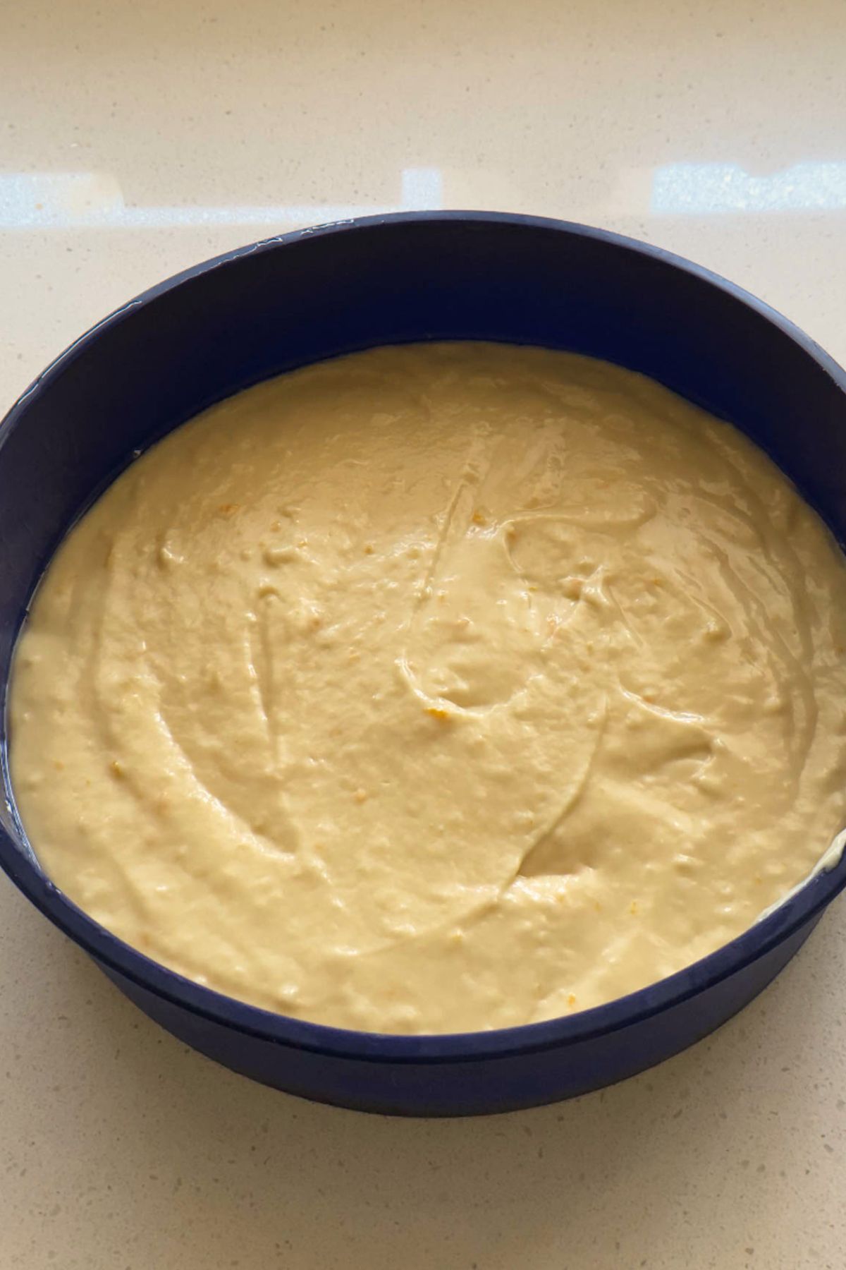 Cake batter in a blue silicone cake pan.