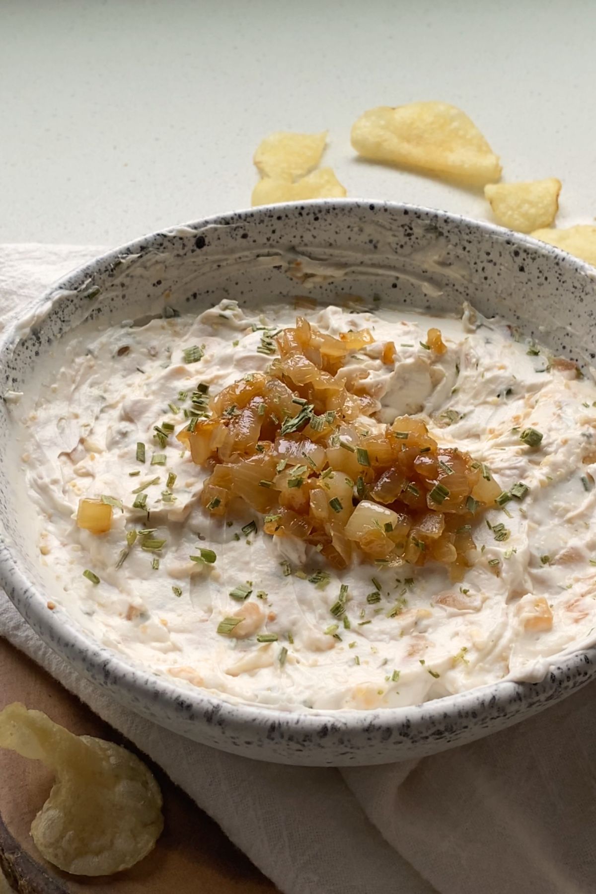 Vegan French onion dip in a white bowl topped with caramelized onions.