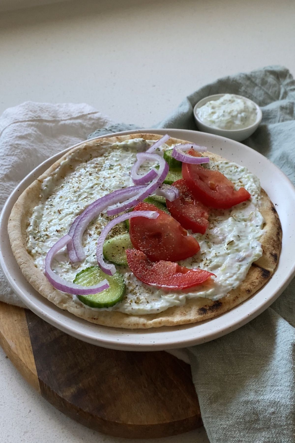 A pita topped with tzatziki, tomato, cucumber, and red onion.