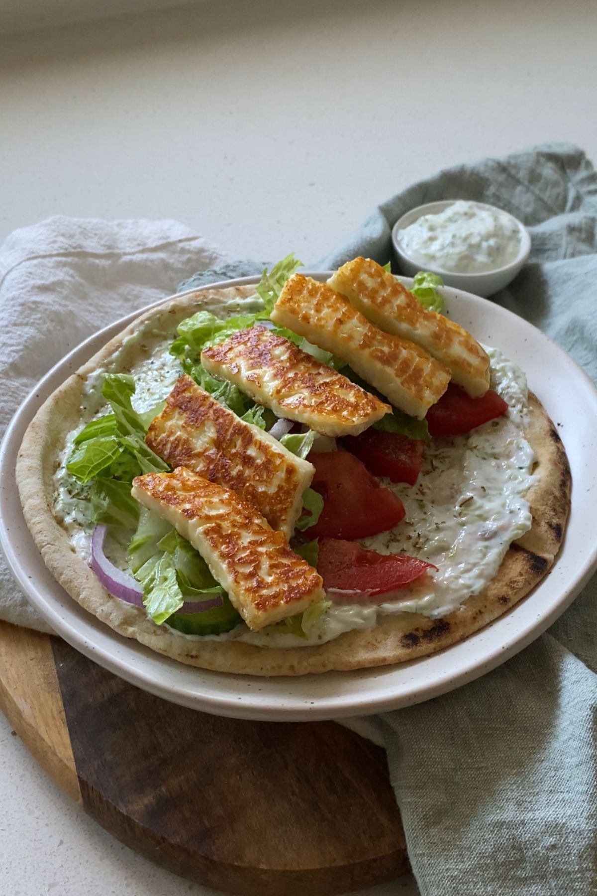 A pita topped with tzatziki, vegetables and grilled halloumi cheese.