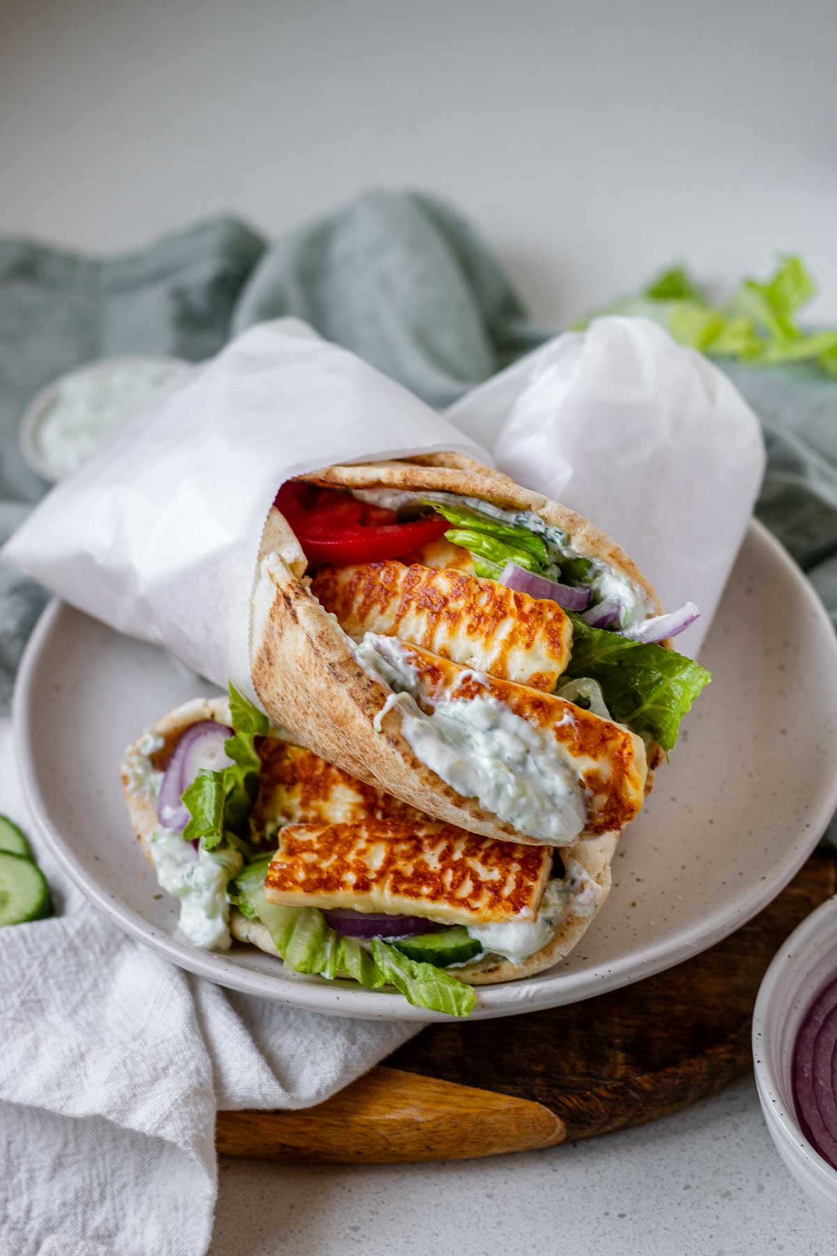 A halloumi gyro stuffed with tzatziki and vegetables. wrapped in parchment paper.