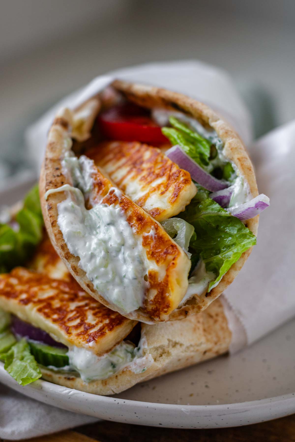 A halloumi gyro stuffed with tzatziki and vegetables. wrapped in parchment paper.