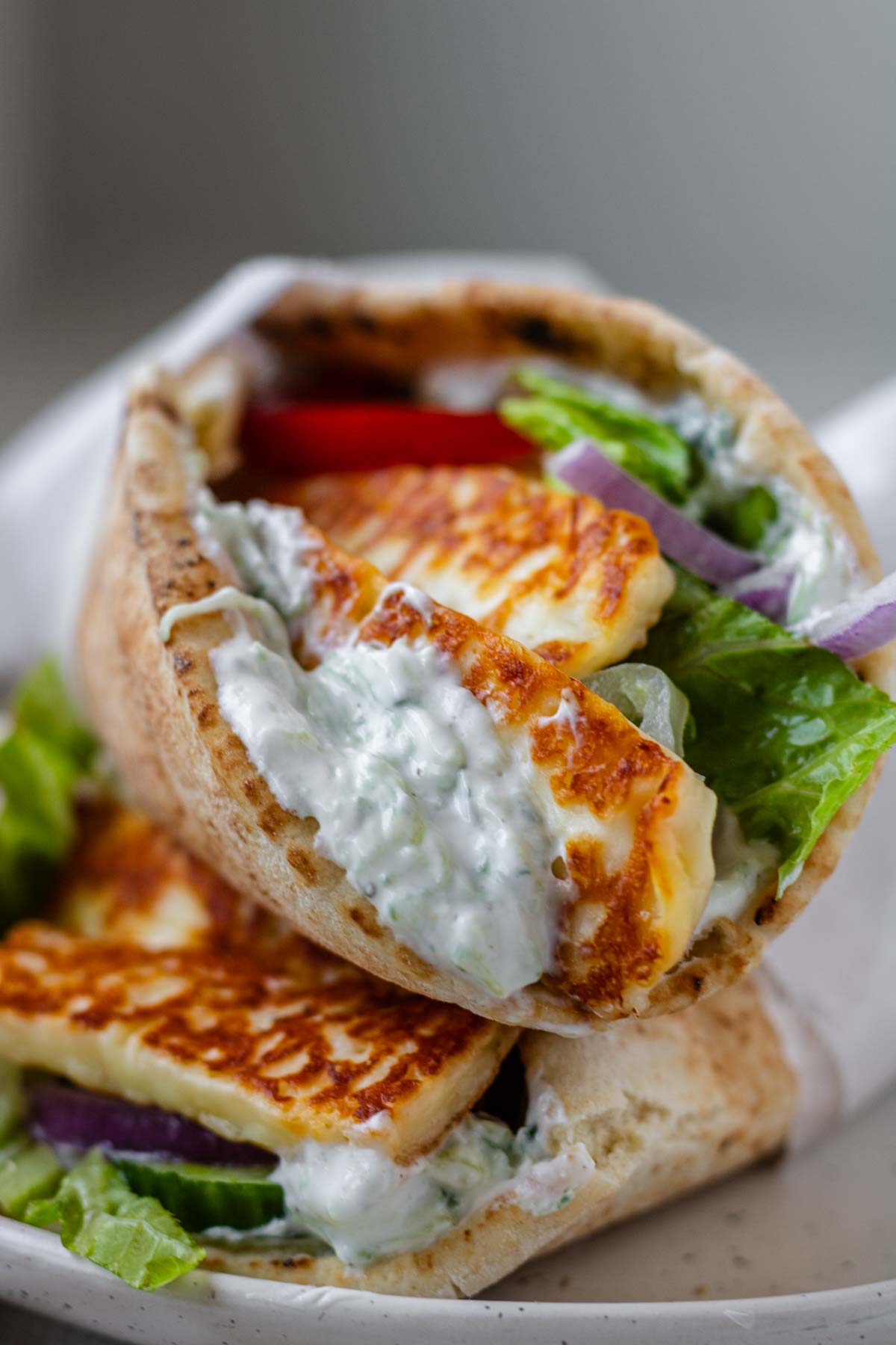 A close up of a halloumi gyro stuffed with tzatziki and vegetables.