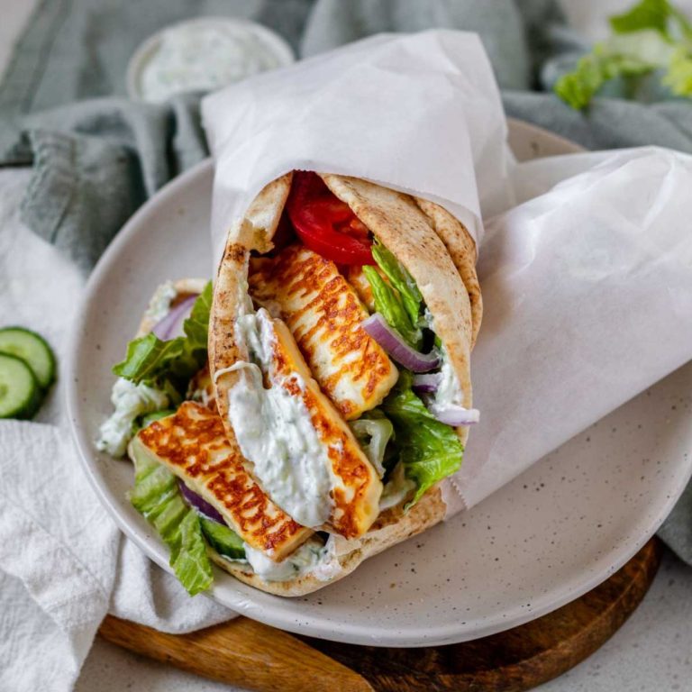 A halloumi gyro stuffed with tzatziki and vegetables. wrapped in parchment paper.