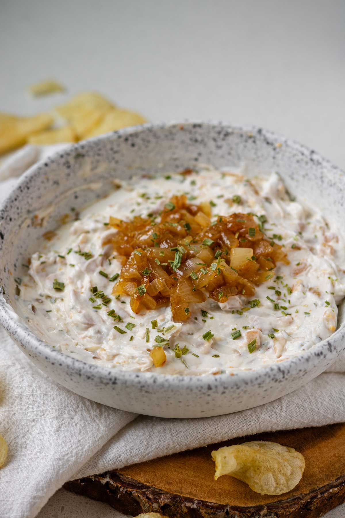A white bowl of French onion dip topped with caramelized onions.