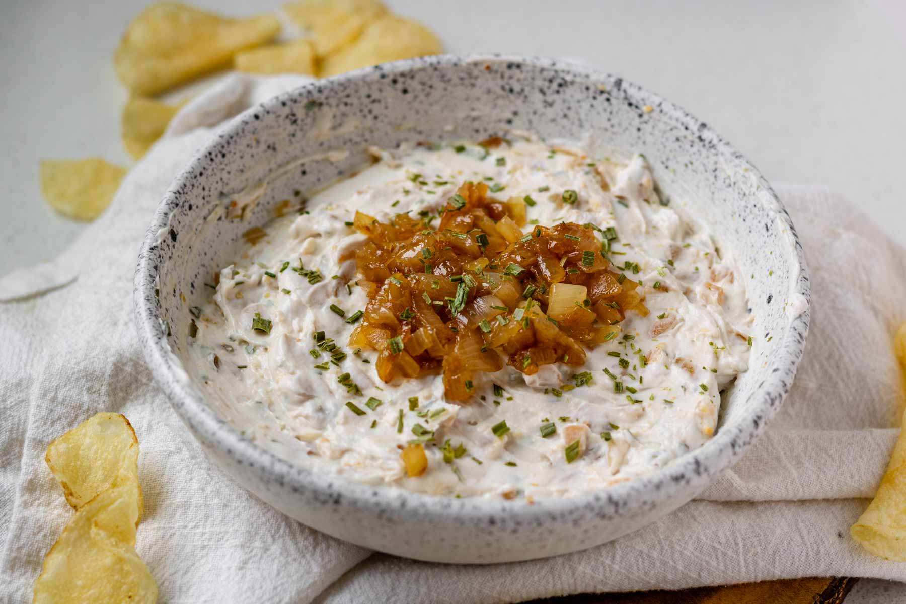 A white bowl of French onion dip topped with caramelized onions.