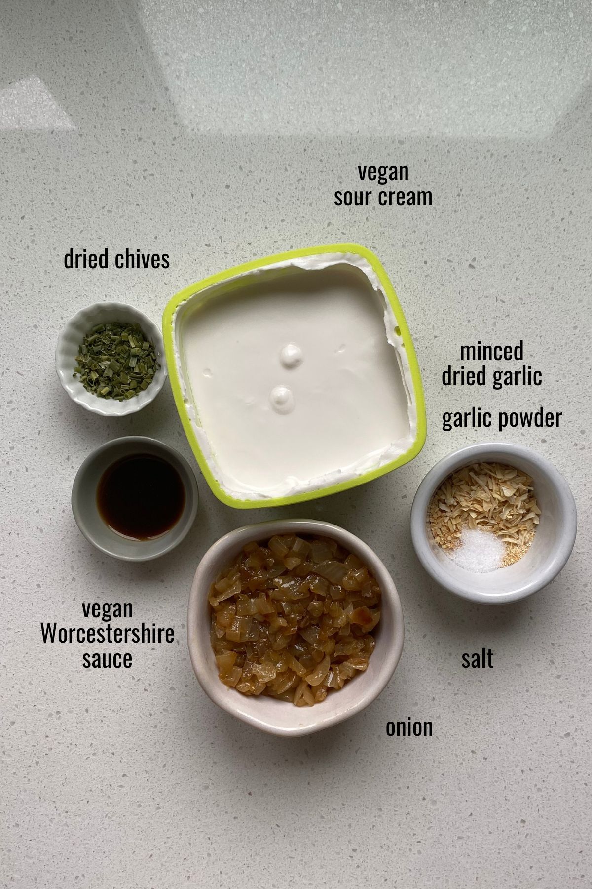 Ingredients for vegan French onion dip in bowls on a white counter top.