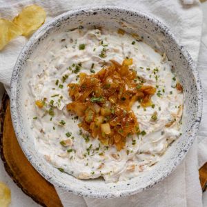 A white bowl of French onion dip topped with caramelized onions.