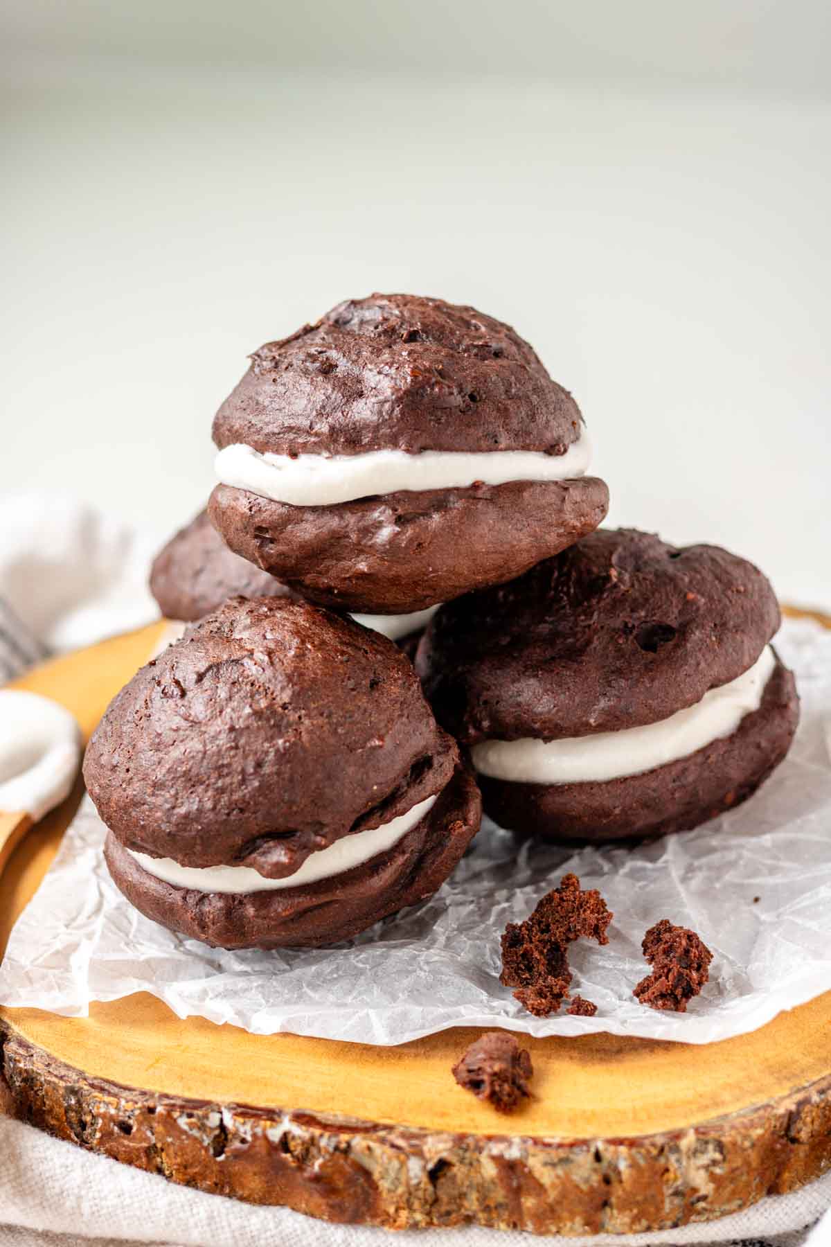 Vegan whoopie pies on a piece of parchment paper on a wooden platter.