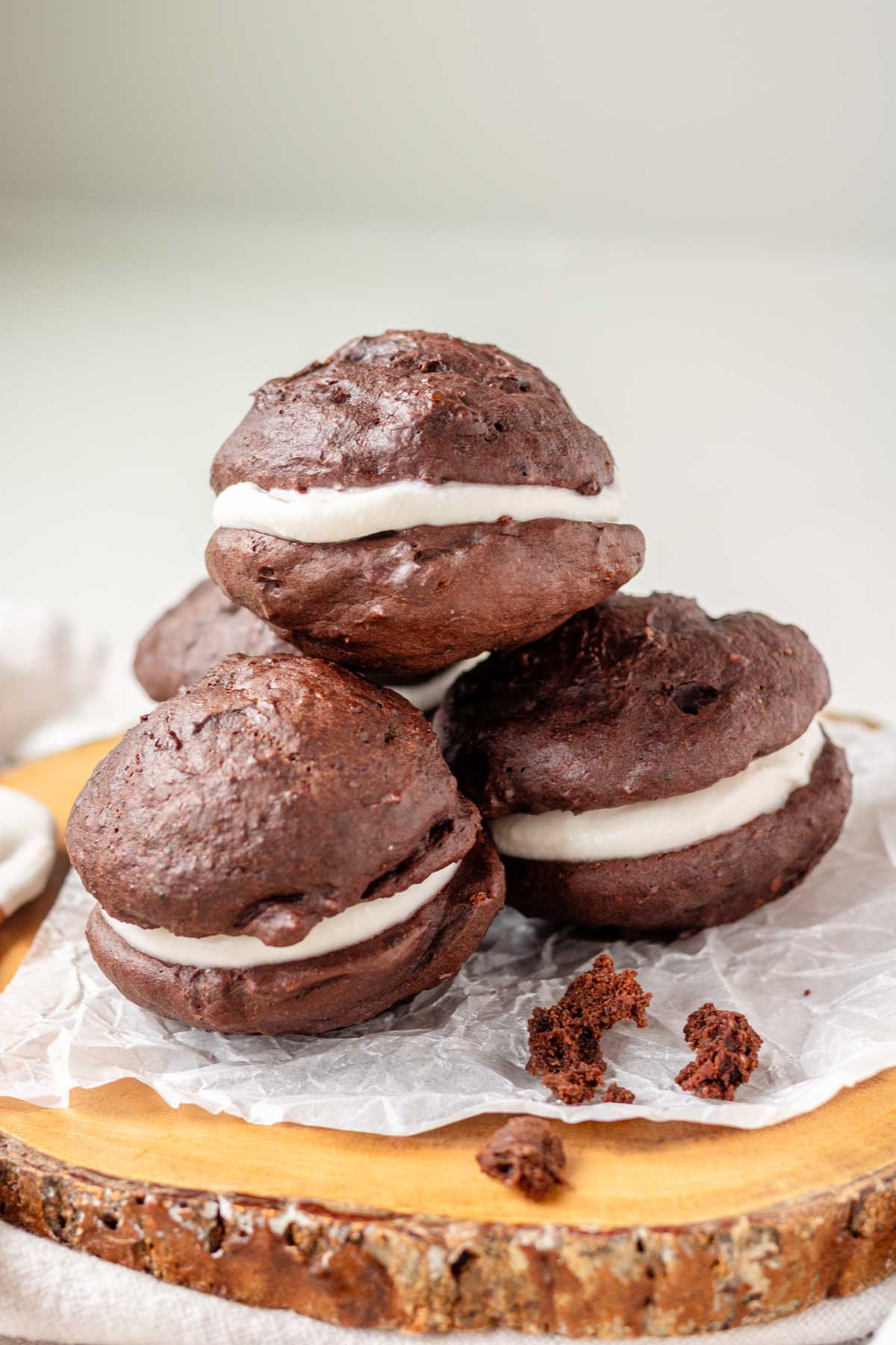 Vegan whoopie pies on a piece of parchment paper on a wooden platter.