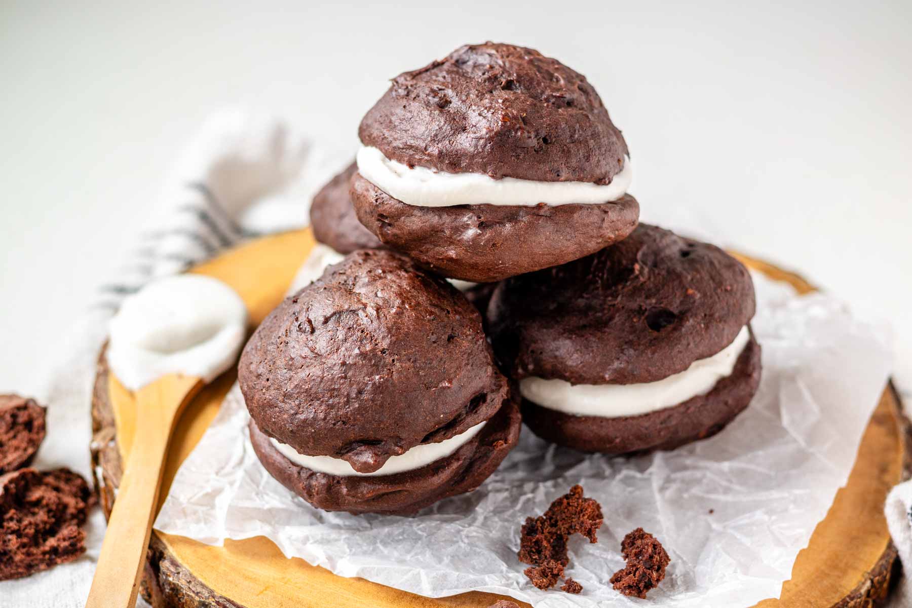 Vegan whoopie pies on a piece of parchment paper on a wooden platter.