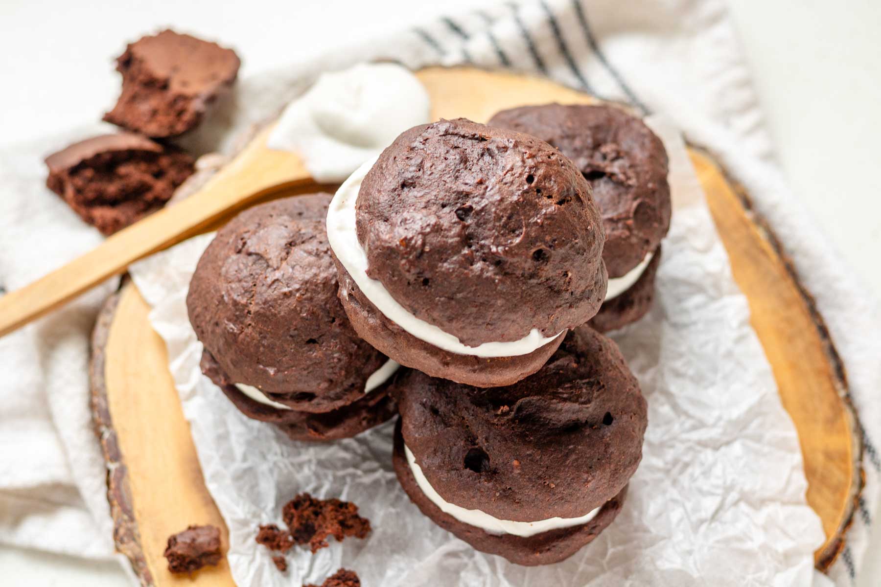 Vegan whoopie pies on a piece of parchment paper on a wooden platter.